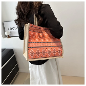 Detail of orange ethnic canvas tote bag with geometric patterns and woven handles