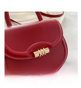 Close-up of a red glossy leather handbag featuring a golden cylindrical wave lock