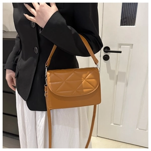 Close-up of caramel quilted crossbody bag with dual straps on a stylish model outfit