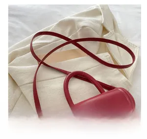 Close-up of a red PU leather crossbody bag featuring a golden twist lock and thin strap