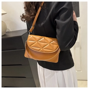 Detail view of caramel brown crossbody bag featuring triangle quilted pattern and dual straps