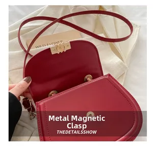 Detail of red matte leather saddle bag showing the magnetic metal clasp closure
