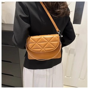 Rear view of model wearing brown quilted leather crossbody bag with geometric stitching