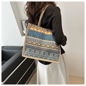 Detail of bohemian tote bag with geometric patterns and braided rope handles on model