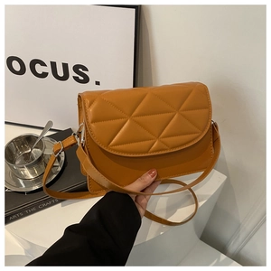 Detail of orange quilted crossbody bag featuring modern geometric patterns and silver metal lock