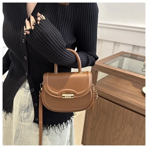 Detailed macro view of the brown saddle bag with a polished golden metallic rotary clasp