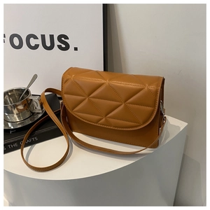 Detailed close-up of quilted caramel crossbody bag with triangular stitching on white pedestal