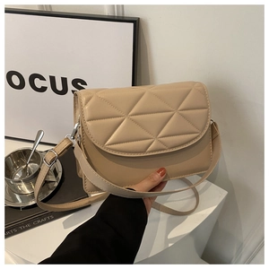 Detail shot of beige quilted shoulder bag with geometric stitching and leather strap