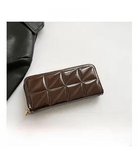 Detail shot of a chocolate brown patent leather wallet with geometric quilted stitching