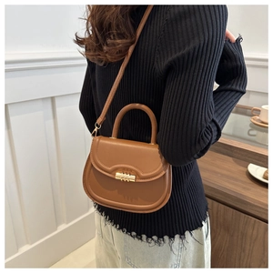 Detail of vintage brown saddle bag with gold metal buckle shown from a side-rear angle