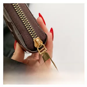 Macro detail of high-quality golden metal zipper on a brown glossy leather crossbody bag