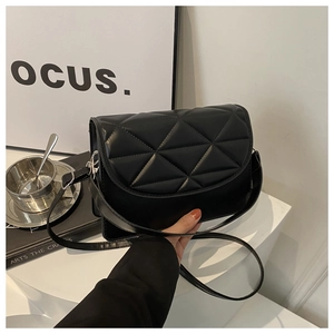 Detail of classic black quilted shoulder bag with triangular stitching and silver hardware