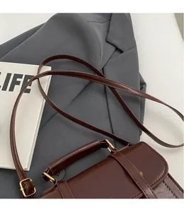 Detail of vintage brown leather bag showing the golden metal ring buckle and smooth long strap