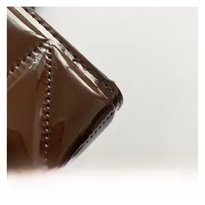 Close-up of dark brown quilted patent leather with high-gloss finish and neat stitching