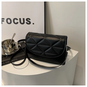 Minimalist black quilted faux leather crossbody bag displayed on a modern white pedestal