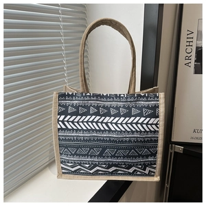 Detail of a geometric pattern tote bag featuring woven jute handles and ethnic style design