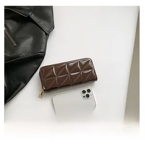 Detail view of coffee brown quilted wallet with gold zipper and phone for scale