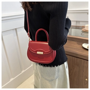 Fashionable red saddle bag with gold buckle shown on a model in a modern interior