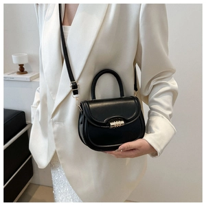 Close-up of black saddle bag with golden multi-loop lock and matte leather texture