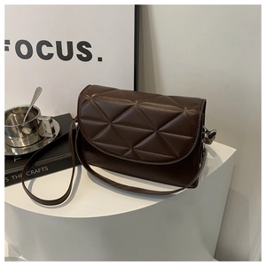 Macro view of dark brown quilted shoulder bag with geometric triangular stitching detail