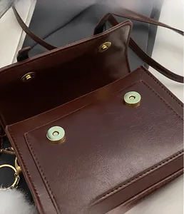 Close-up of brown leather bag featuring dual magnetic gold hardware snap closures