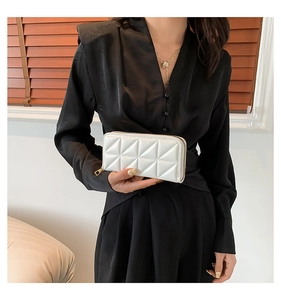 Detail of white clutch bag featuring geometric triangle quilted texture and gold zipper