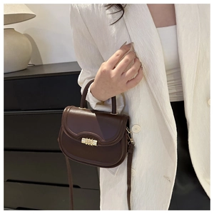 Detail of vintage brown saddle bag with golden clasp and smooth leather texture
