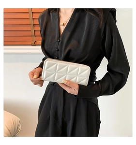 Close-up of white long wallet with geometric diamond texture held by model