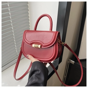 Detail of red saddle bag with matte leather finish and golden triple ring buckle