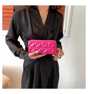 Macro shot of rose pink quilted leather clutch with gold zipper and diamond pattern