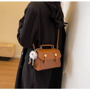 Λεπτομέρεια καφέ vintage τσάντας με λευκό λούτρινο κρεμαστό σε ξύλινο δάπεδο