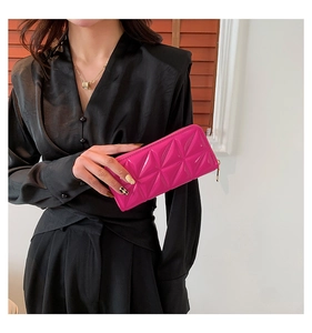 Detail of rose red quilted long wallet with geometric patterns and golden zipper closure