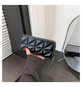 Detail of black glossy long wallet with geometric quilting and golden zipper closure