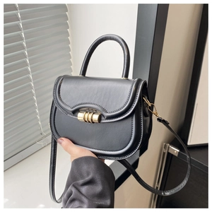 Detail of the black saddle bag featuring a unique gold cylindrical rotating buckle and handle