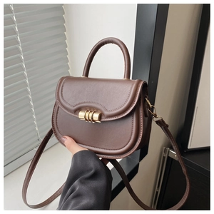Close-up of vintage brown saddle bag featuring smooth texture and gold metal buckle detail
