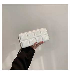 Detail of white geometric quilted wallet with golden zipper closure and glossy finish