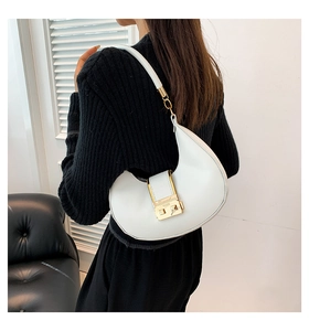 Close-up of a white crescent shoulder bag with gold metal buckle shown on a model