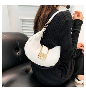 Close-up of white crescent shoulder bag with large gold buckle and smooth leather texture