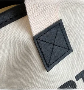 Detail of cross-stitch reinforcement on canvas tote bag with black faux leather handle