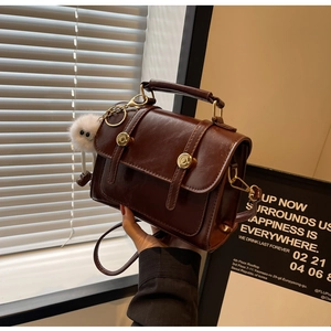 Λεπτομέρεια vintage σκούρα καφέ τσάντα messenger με δερμάτινα λουριά και λευκό γούνινο