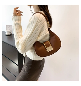 Detail of caramel brown crescent shoulder bag with golden metal buckle and leather strap