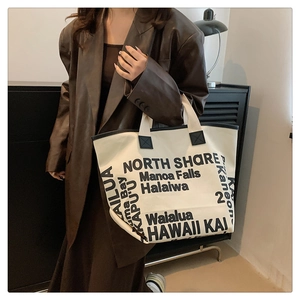 Vue détaillée du sac cabas en toile avec imprimé de lettres noires sur un mannequin