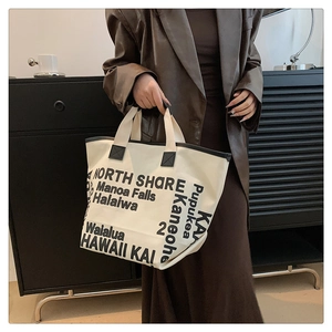 Détail du sac cabas en toile blanc cassé avec typographie noire et anses solides