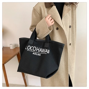Photo de style d'un grand sac cabas en toile noire avec inscription logo blanche