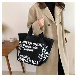 Détail du sac cabas en toile noire avec imprimé Hawaii porté par un mannequin en manteau
