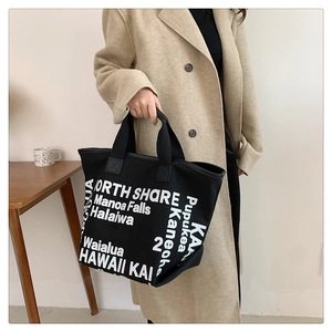 Détail du cabas en toile noire avec typographie Hawaii blanche et bandoulières renforcées