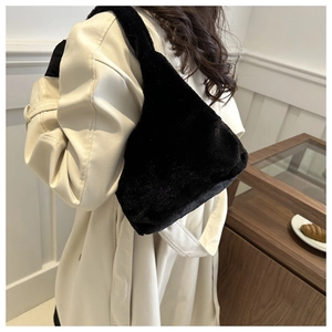 Close-up of black fuzzy plush shoulder bag styled with a beige trench coat for winter