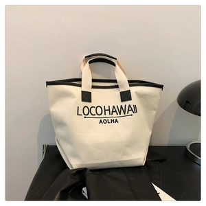 Close-up of LOCOHAWAII printed canvas bucket bag with black leather trim and handles