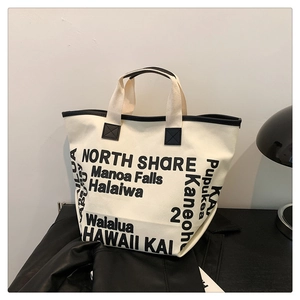 Détail du sac cabas en toile avec impressions de lettres noires et finitions en cuir