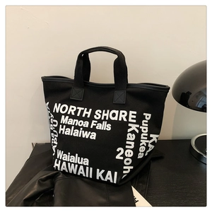 Détail du sac cabas en toile noire avec imprimé de noms de lieux de Hawaï en blanc